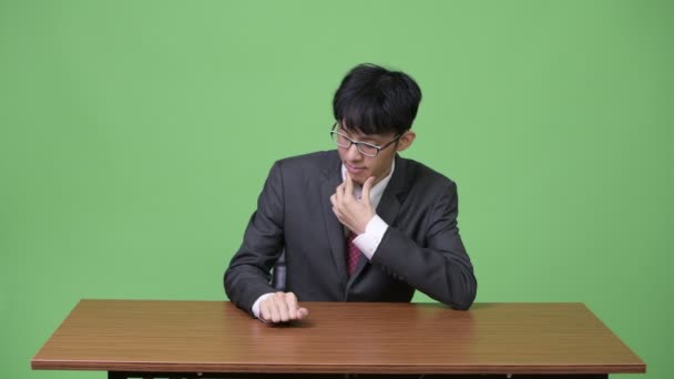 Ung asiatisk affärsman uttråkad och trumma med fingrarna på bord — Stockvideo