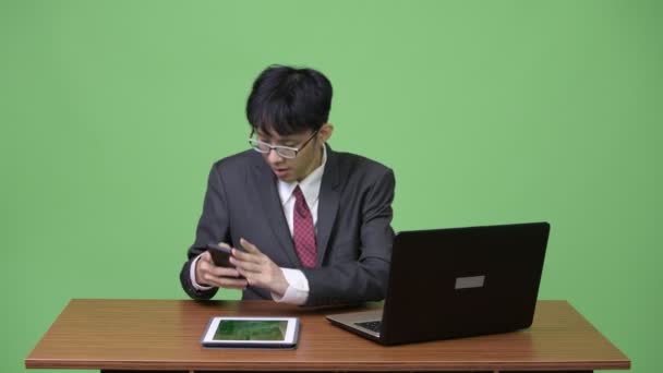 Junge glückliche asiatische Geschäftsmann video telefonieren mit Telefon während der Arbeit — Stockvideo