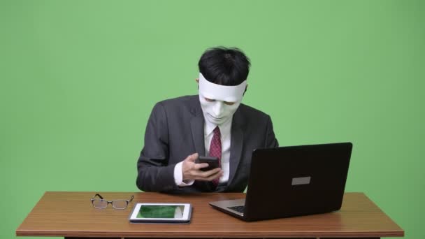 Хакер бізнесмен носить маску і використовує електронні пристрої разом — стокове відео