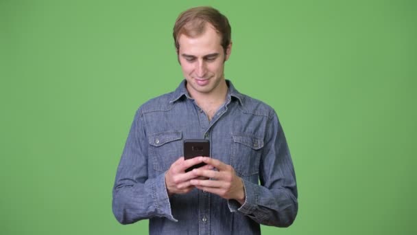 Joven hombre feliz sonriendo mientras usa el teléfono — Vídeos de Stock