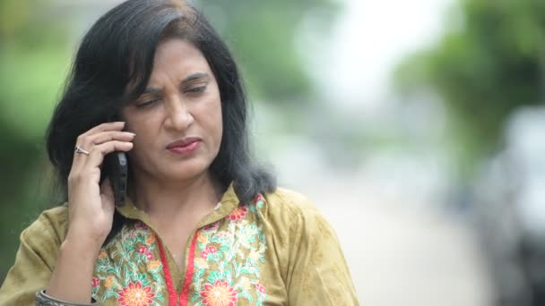 Зрелая красивая индийская женщина разговаривает по телефону на улице — стоковое видео