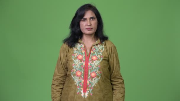 Зрелая красивая индийская женщина в традиционной одежде на зеленом фоне — стоковое видео