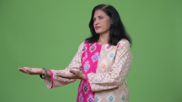 Зрелая красивая индийская женщина показывает что-то в сторону — стоковое видео