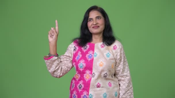 Mature happy beautiful Indian woman thinking while pointing finger up — Stock Video