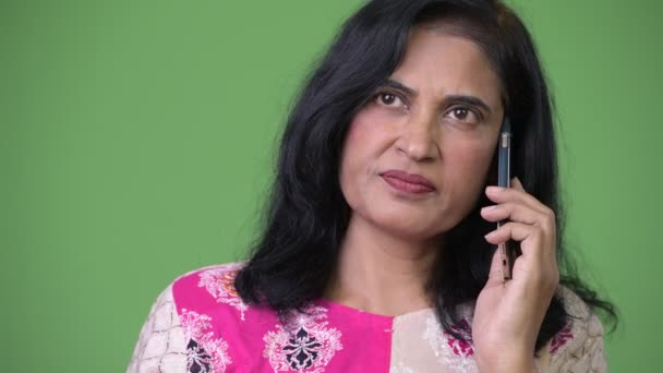 Зрелая красивая индийская женщина думает, разговаривая по телефону — стоковое видео