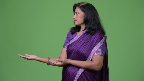 Madura hermosa mujer india mostrando algo mientras usa ropa tradicional Sari — Vídeos de Stock