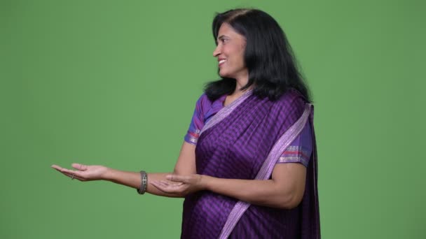 Dojrzałe szczęśliwy piękny Indian kobieta pokazując coś podczas noszenia tradycyjnych ubrania Sari — Wideo stockowe
