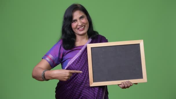 Mature happy beautiful Indian woman pointing to blackboard — Stock Video