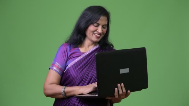 Ώριμη ευτυχής όμορφη ινδική γυναίκα χαμογελώντας ενώ χρησιμοποιούν φορητό υπολογιστή — Αρχείο Βίντεο