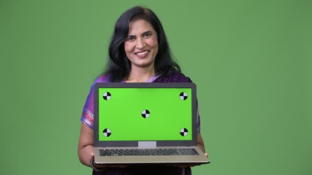 Mature happy beautiful Indian woman smiling while showing laptop — Stock Video