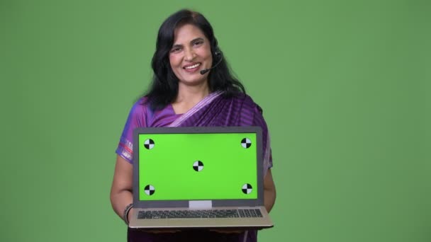 Mature happy beautiful Indian woman as call center representative showing laptop — Stock Video