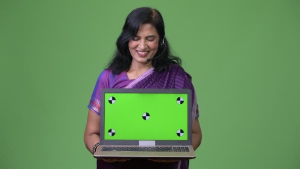 Mature happy beautiful Indian woman as call center representative showing laptop — Stock Video