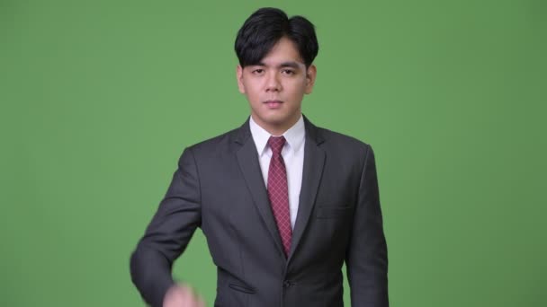 Young handsome Asian businessman pointing finger up — Stock Video