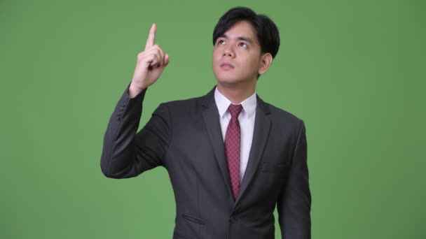 Genç yakışıklı Asya iş adamı işaret parmağı yukarıya — Stok video