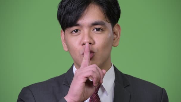 Jonge knappe Aziatische zakenman met de vinger op de lippen — Stockvideo