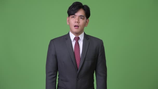 Молодий красивий азіатських бізнесмен дивлячись нудно — стокове відео