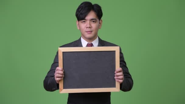 Junge hübsche asiatische Geschäftsmann zeigt Tafel — Stockvideo