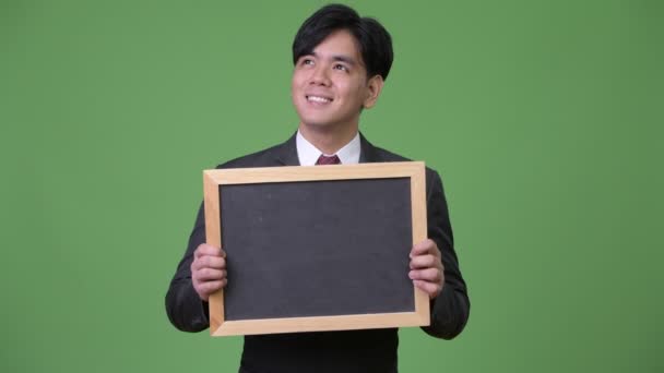 若いハンサムなアジア系のビジネスマンを示す黒板 — ストック動画