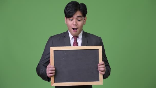 Young handsome Asian businessman showing blackboard — Stock Video