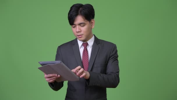 デジタル タブレットを使用して若いハンサムなアジア系のビジネスマン — ストック動画