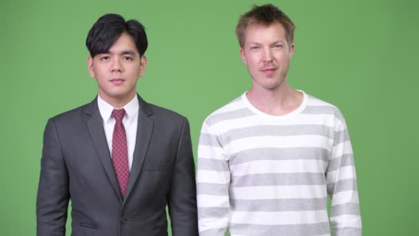 若いアジア系のビジネスマンおよび緑の背景にクロマキーに対して一緒に若いスカンジナビア ビジネスマンのスタジオ撮影 — ストック動画