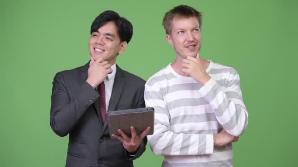 Young handsome Asian businessman and young Scandinavian businessman working together — Stock Video