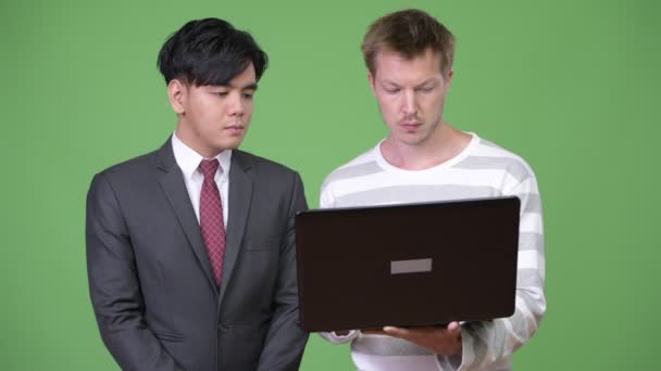 Ung Vacker asiatisk affärsman och unga skandinaviska affärsman som arbetar tillsammans — Stockvideo