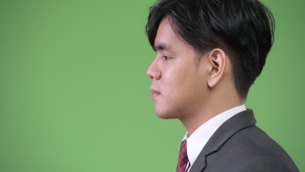 Jonge knappe Aziatische zakenman tegen groene achtergrond — Stockvideo