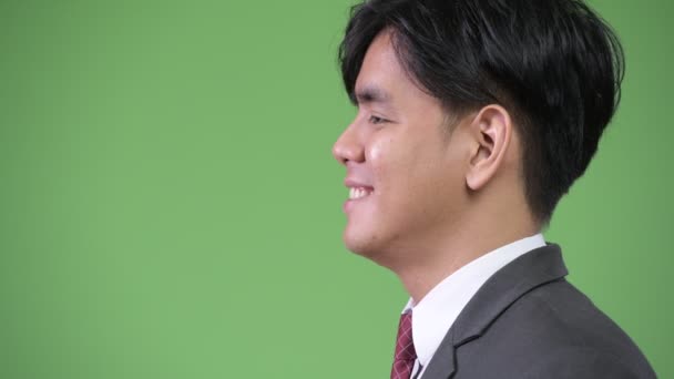 Jonge knappe Aziatische zakenman tegen groene achtergrond — Stockvideo