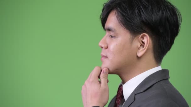 Young handsome Asian businessman against green background — Stock Video