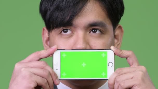 Joven guapo asiático empresario mostrando teléfono móvil — Vídeos de Stock