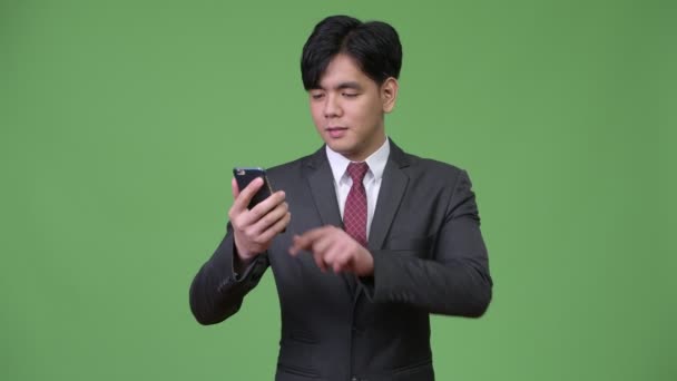 Young handsome Asian businessman using mobile phone — Stock Video