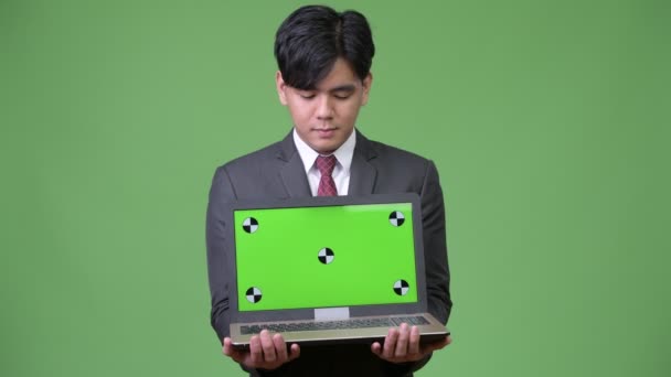 Young handsome Asian businessman showing laptop — Stock Video