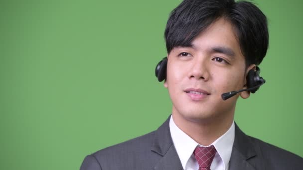 Junger hübscher asiatischer Geschäftsmann arbeitet als Callcenter-Repräsentant — Stockvideo