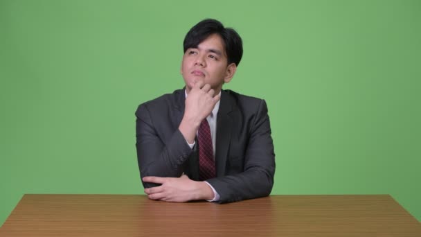 Ung Vacker asiatisk affärsman mot grön bakgrund — Stockvideo