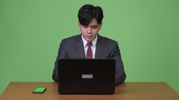 Genç yakışıklı Asya işadamı ile laptop yeşil arka plan çalışma — Stok video