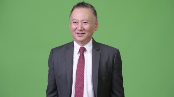 Mature heureux Japonais homme d'affaires souriant tout en pointant du doigt — Video
