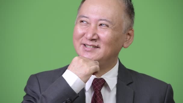 Mature happy Japanese businessman smiling while thinking — Stock Video