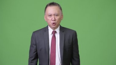 Dudaklarında parmak ile olgun kızgın Japon iş adamı