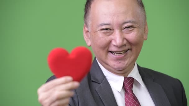 Ώριμη ιαπωνική επιχειρηματίας κρατώντας κόκκινη καρδιά έτοιμη για ημέρα του Αγίου Βαλεντίνου — Αρχείο Βίντεο