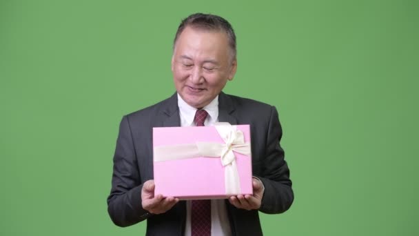 Empresário japonês maduro com caixa de presente contra fundo verde — Vídeo de Stock