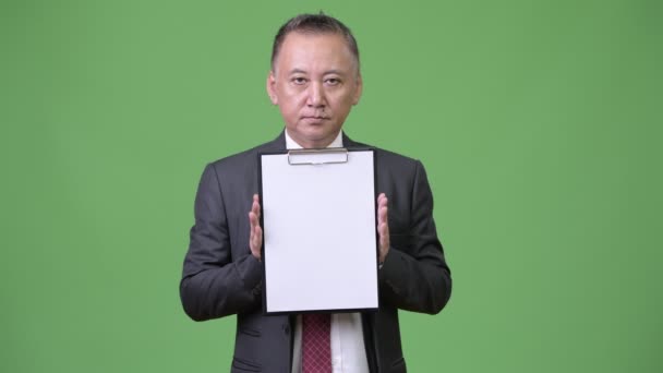 カメラで成熟した日本のビジネスマン表示クリップボード — ストック動画
