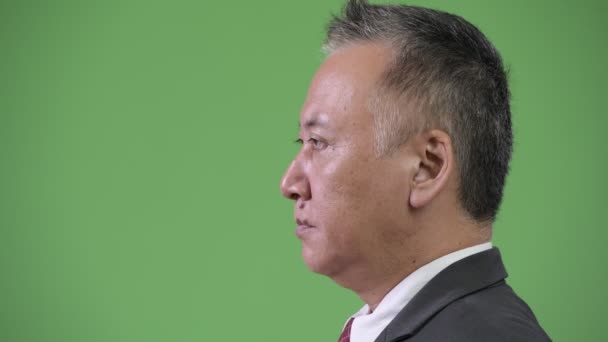 Перегляд профілю зрілих японського бізнесмена проти зелений фон — стокове відео
