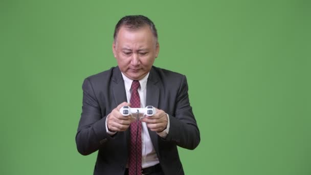 Rijpe Japanse zakenman spelen tegen een groene achtergrond — Stockvideo