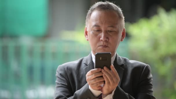 Maturo giapponese uomo d'affari utilizzando telefono in il strade all'aperto — Video Stock