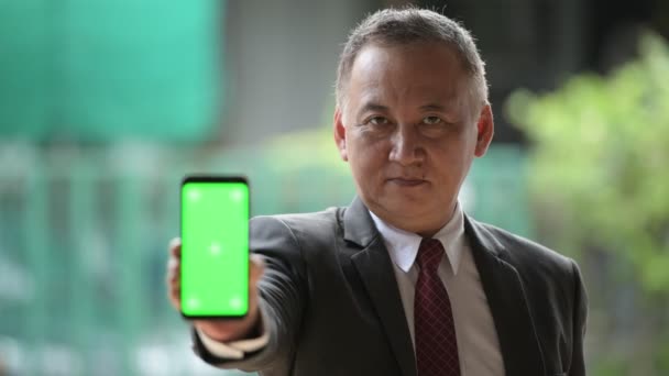 Зрілі японський бізнесмен показ телефон на вулиці, на відкритому повітрі — стокове відео