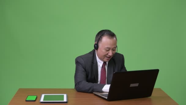 Mature Japanese businessman working as call center representative — Stock Video