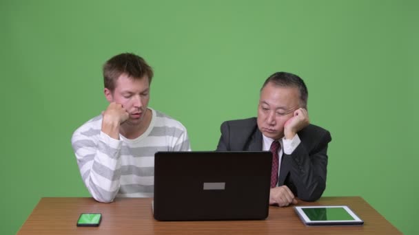 Reifer japanischer Geschäftsmann und junger skandinavischer Geschäftsmann arbeiten zusammen — Stockvideo
