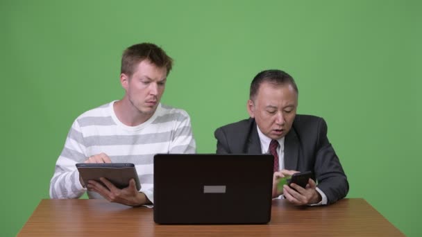 Mogna japansk affärsman och unga skandinaviska affärsman som arbetar tillsammans — Stockvideo