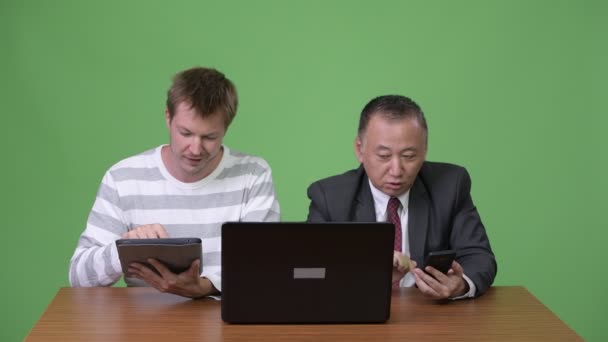 Rijpe Japanse zakenman en jonge Scandinavische zakenman samen te werken — Stockvideo